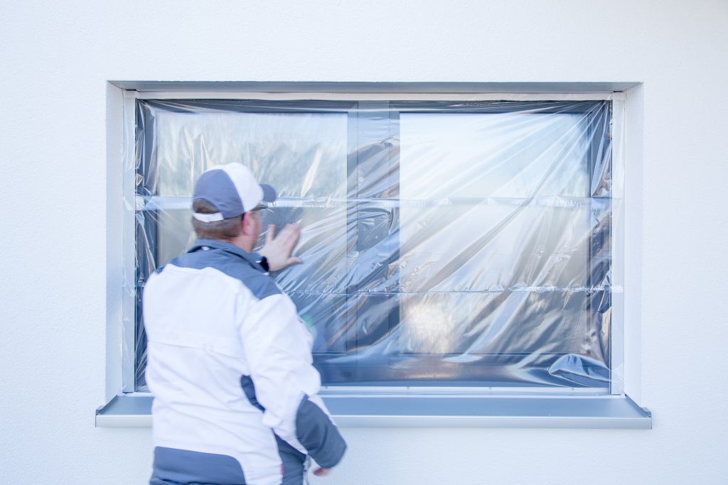 SJ__5335 Ein Maler klebt mit Folie von Klauss-Klebeband ein Fenster ab